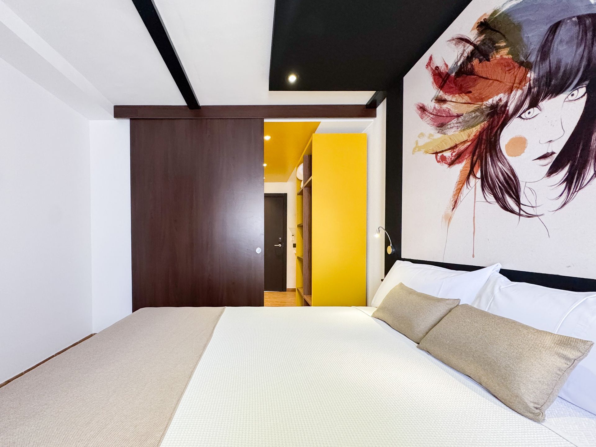 Un dormitorio con una cama y un cuadro de una mujer en la pared.