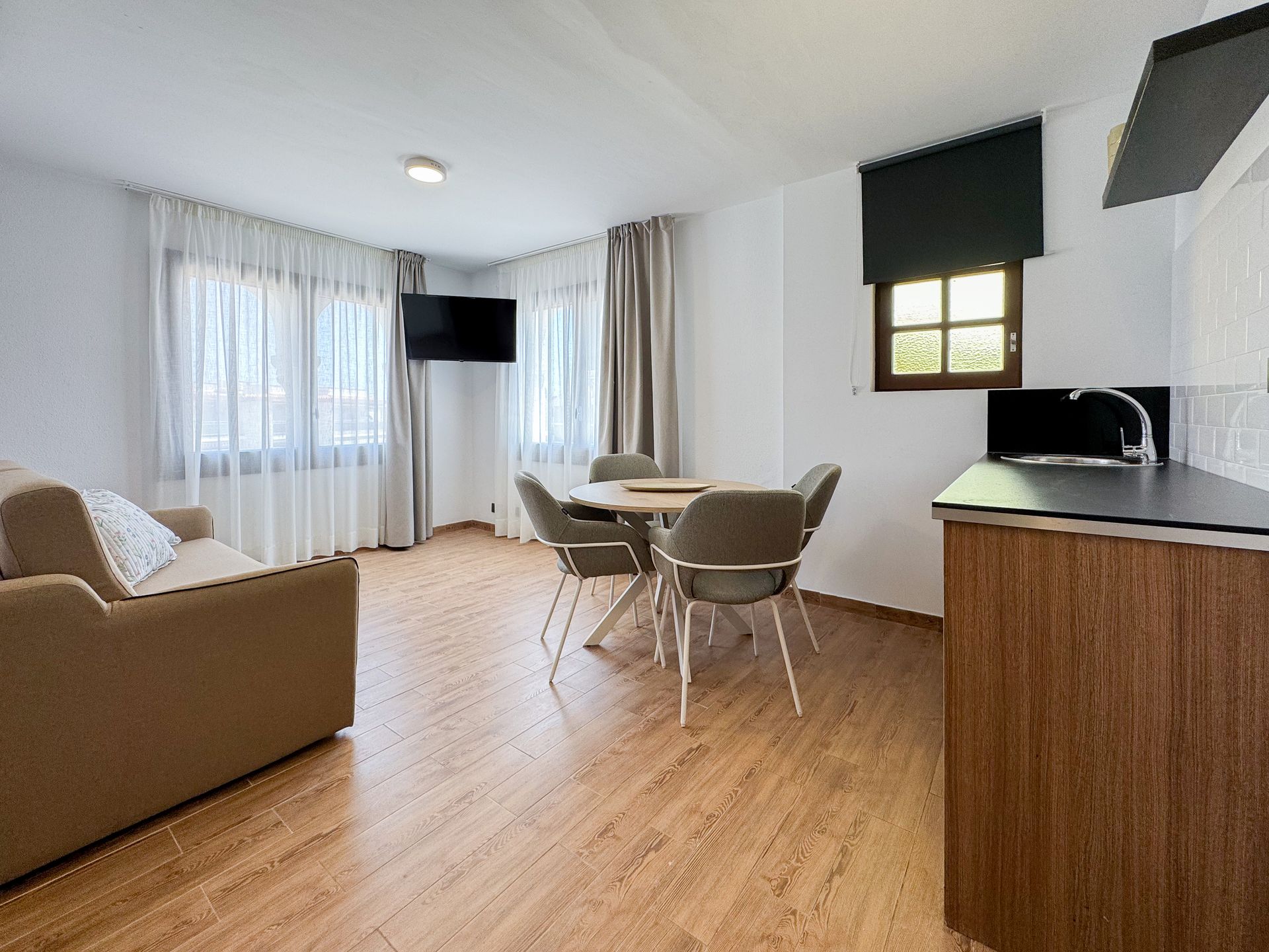 Una sala de estar con un sofá, una mesa, sillas y un televisor.