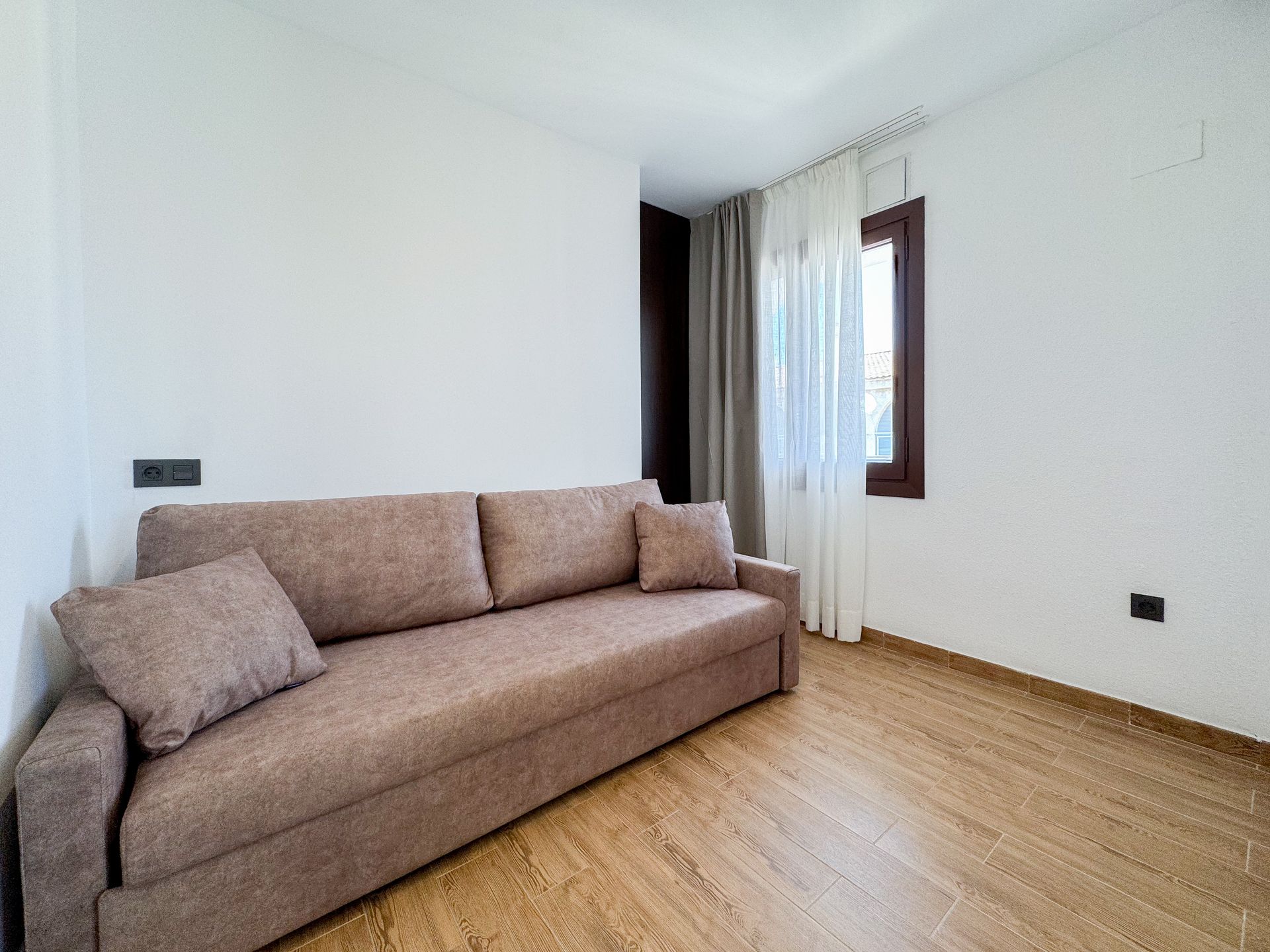 Una sala de estar con un sofá y una ventana.