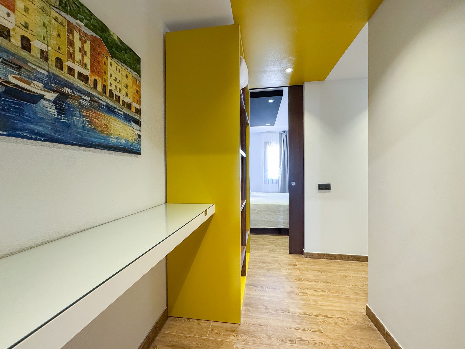 Un pasillo con un estante amarillo y un cuadro en la pared.