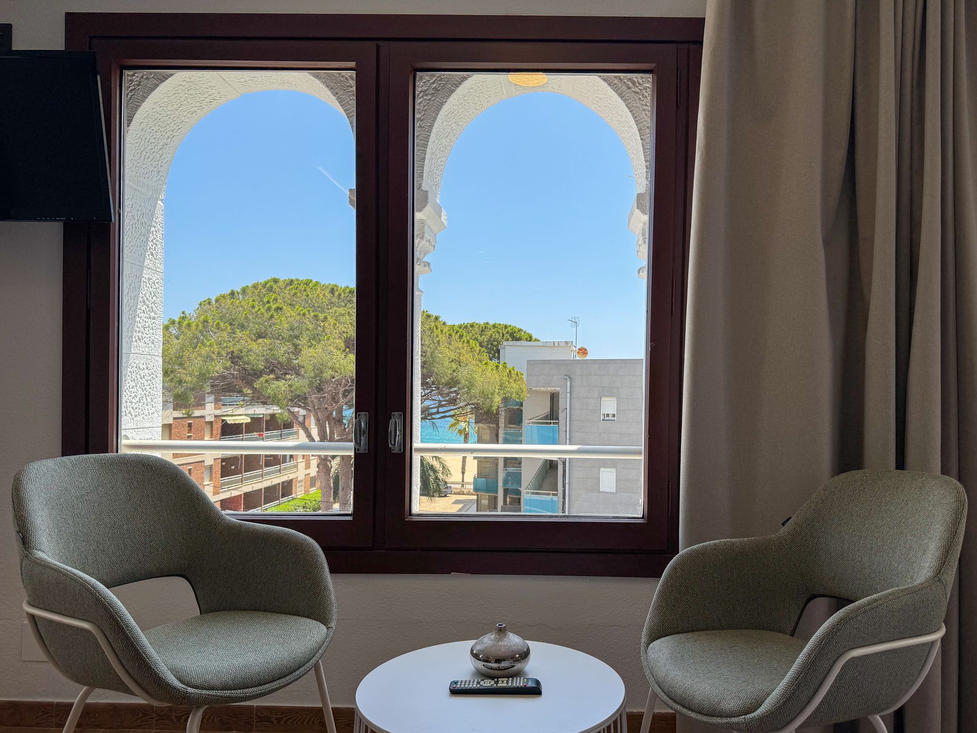 Dos sillas y una mesa frente a una ventana con vista a una ciudad.