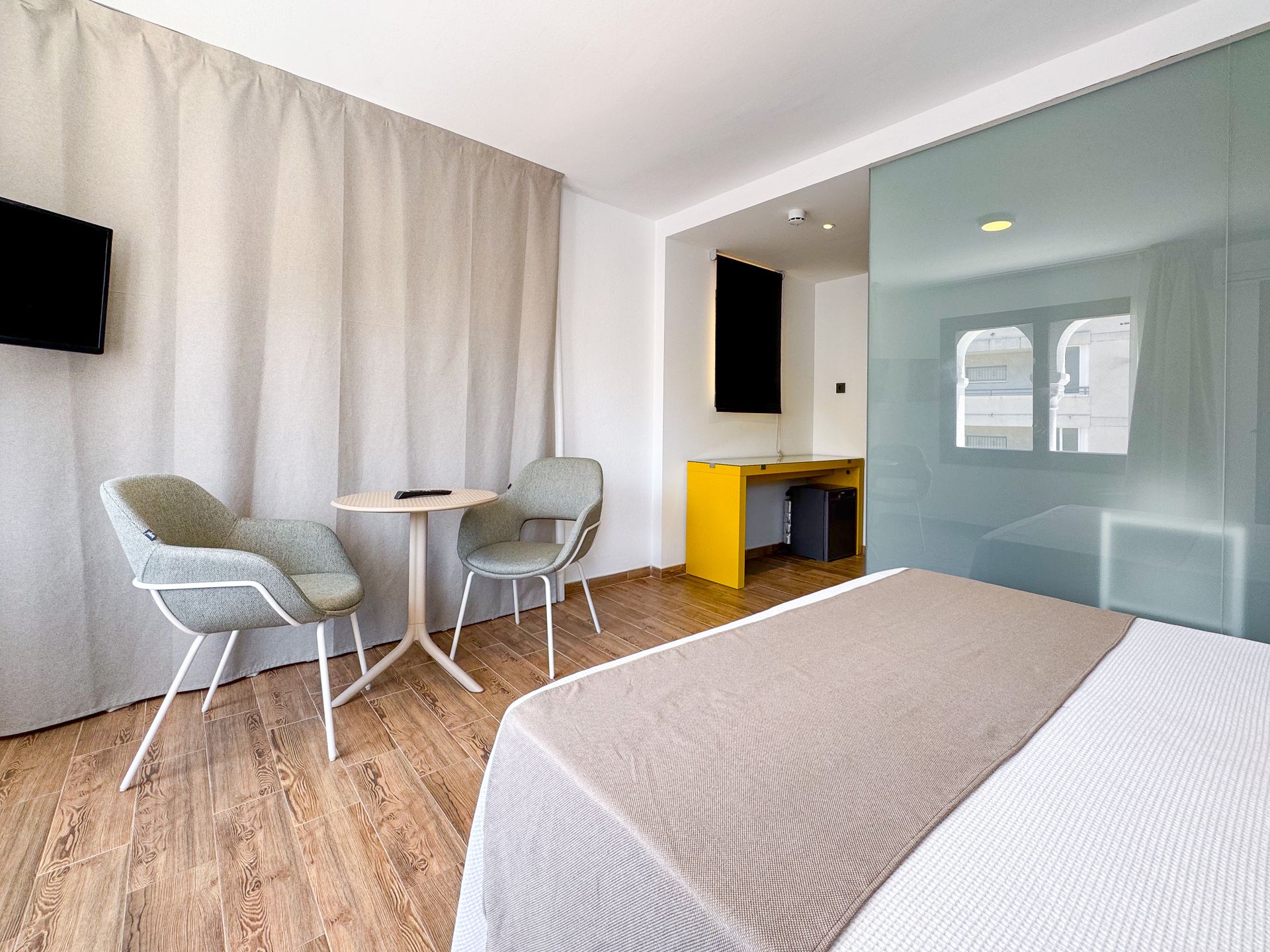 Una habitación de hotel con una cama, sillas, mesa y televisión.