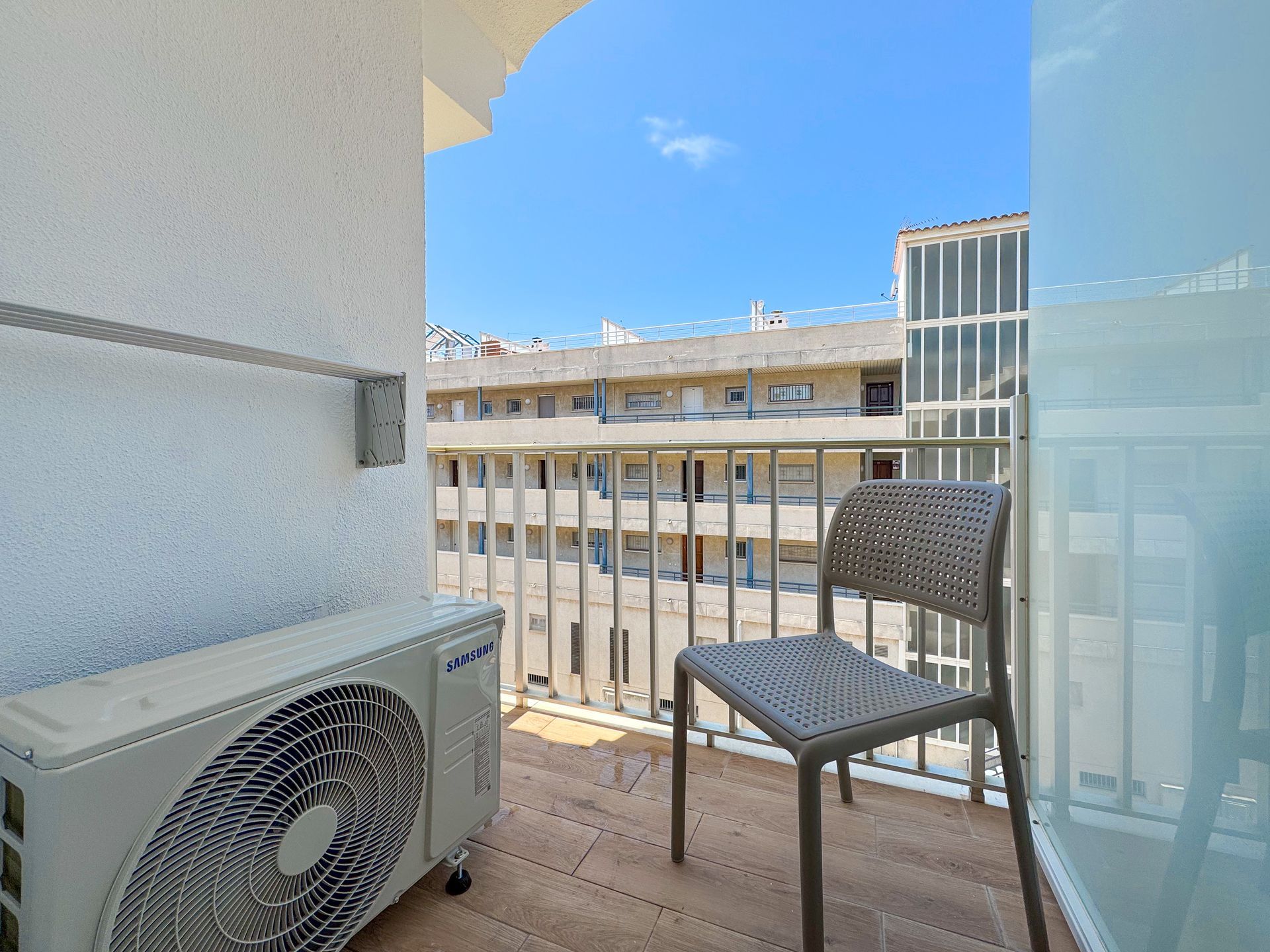 Una silla está sentada en un balcón al lado de un ventilador.