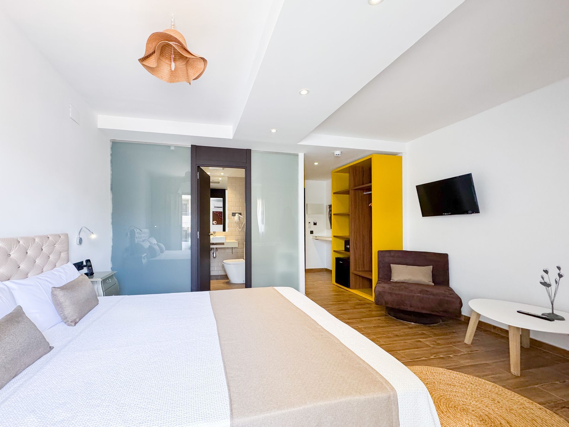 Una habitación de hotel con una cama tamaño king, silla, mesa y televisión.