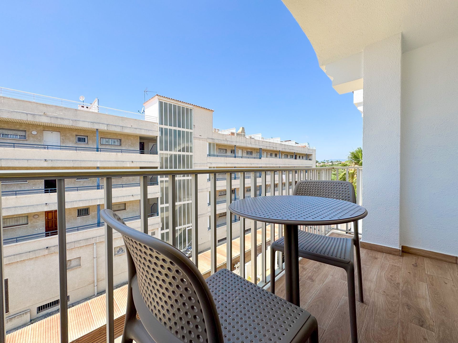 Un balcón con mesa y sillas y vista a un edificio.