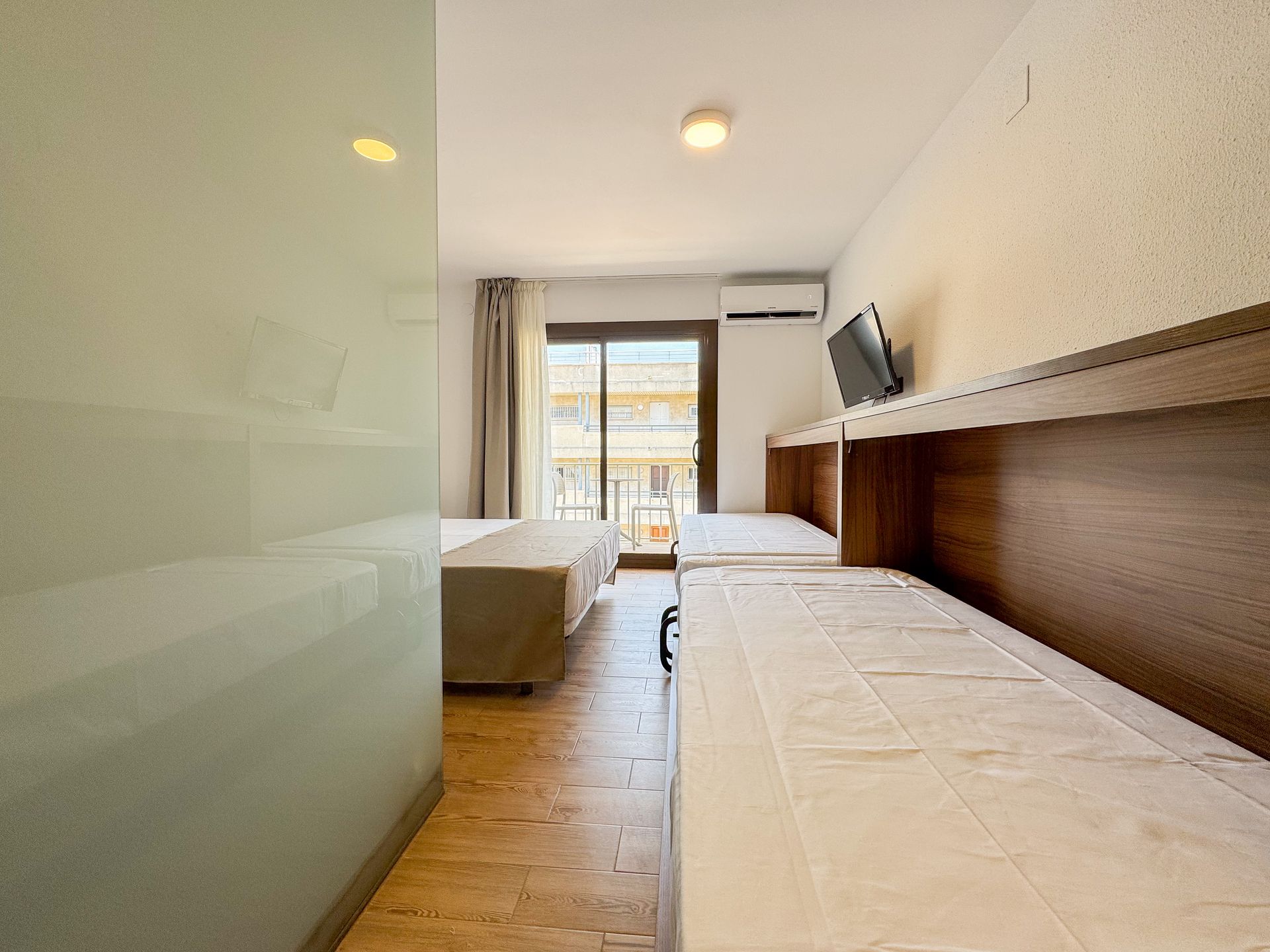 Una habitación de hotel con dos camas y un televisor en la pared.