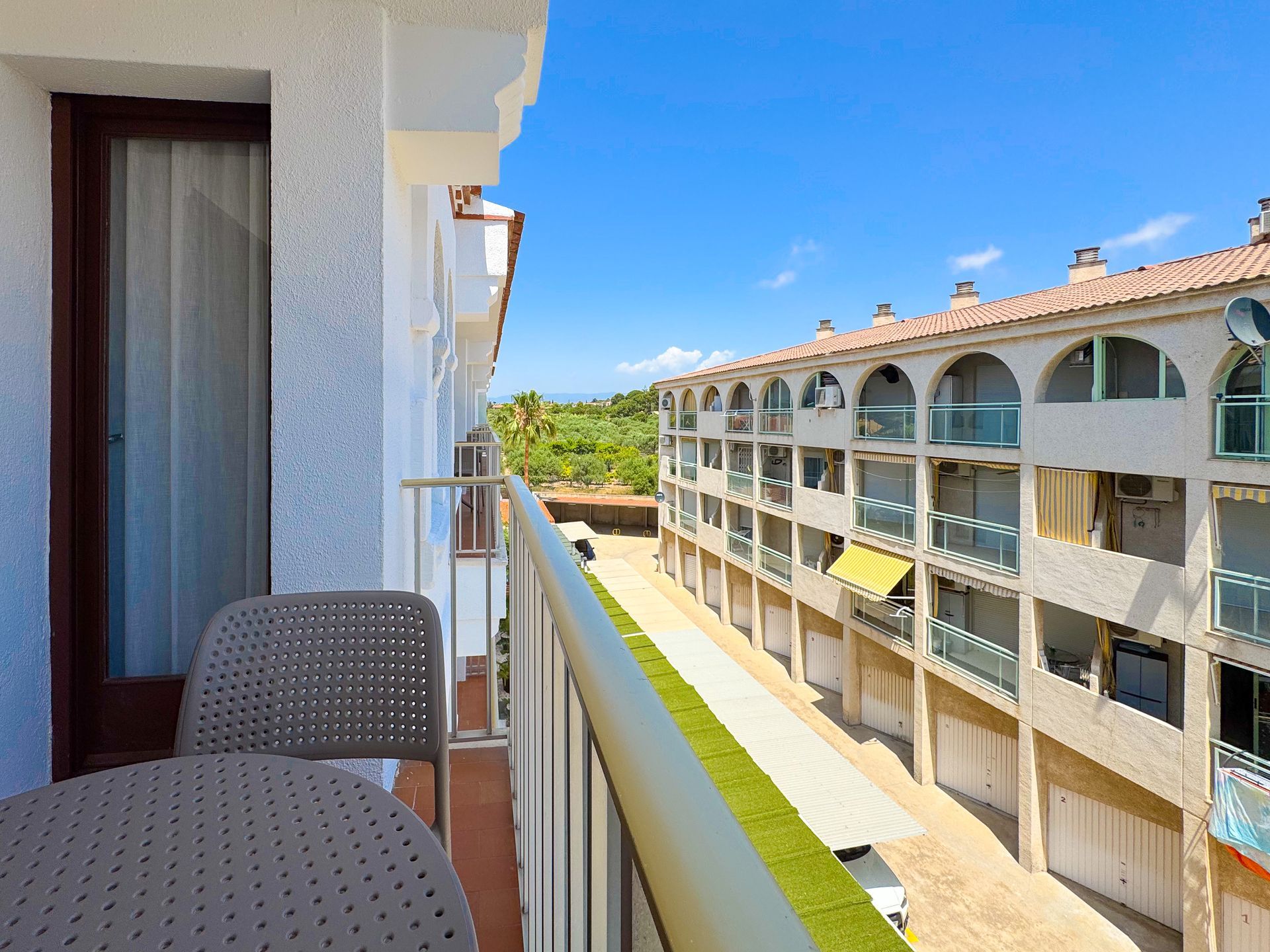 Un balcón con una mesa y sillas con vista a un edificio.