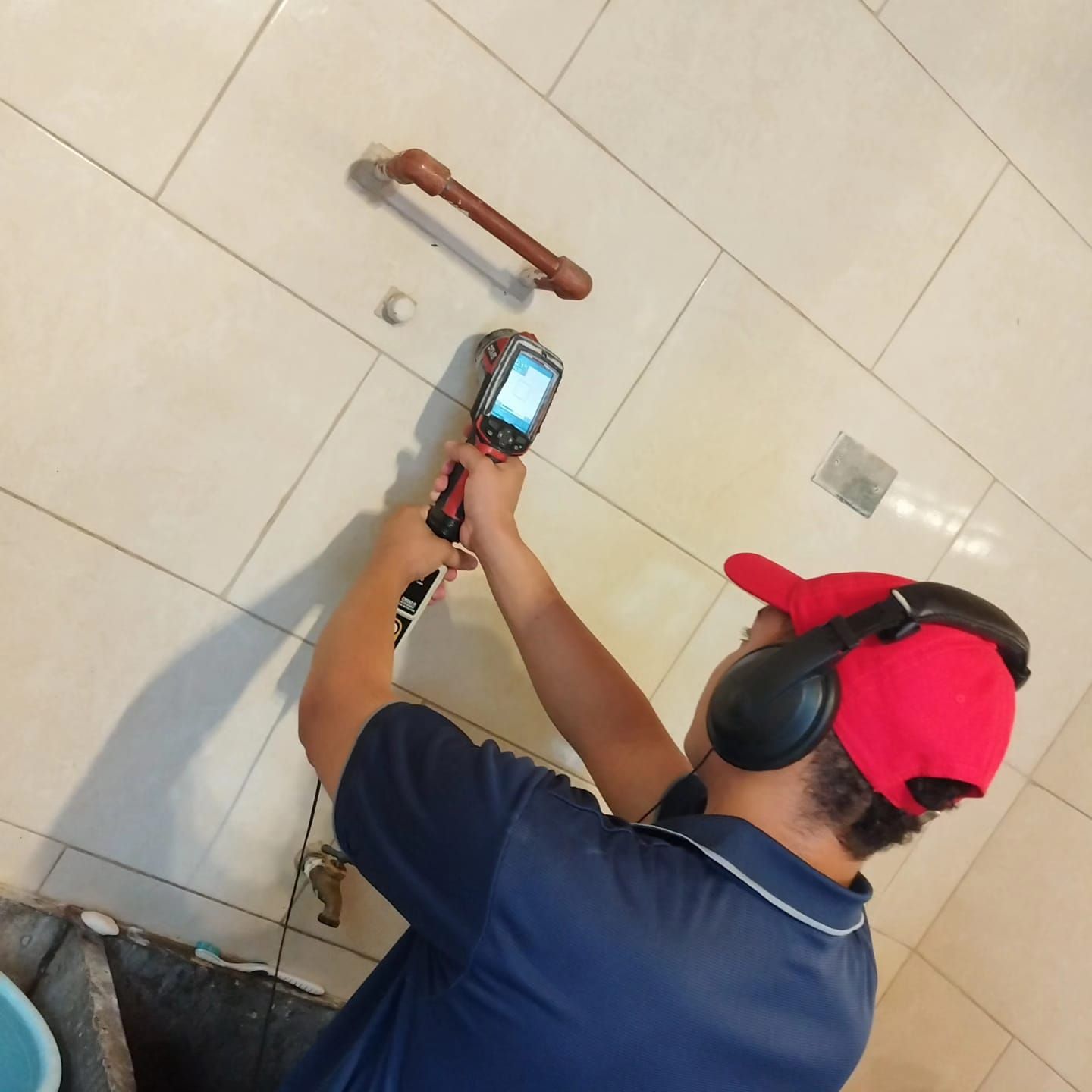 Un hombre con auriculares y un sombrero rojo está trabajando en una pared.
