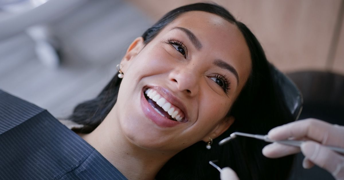 A woman is smiling while having her teeth examined by a dentist.