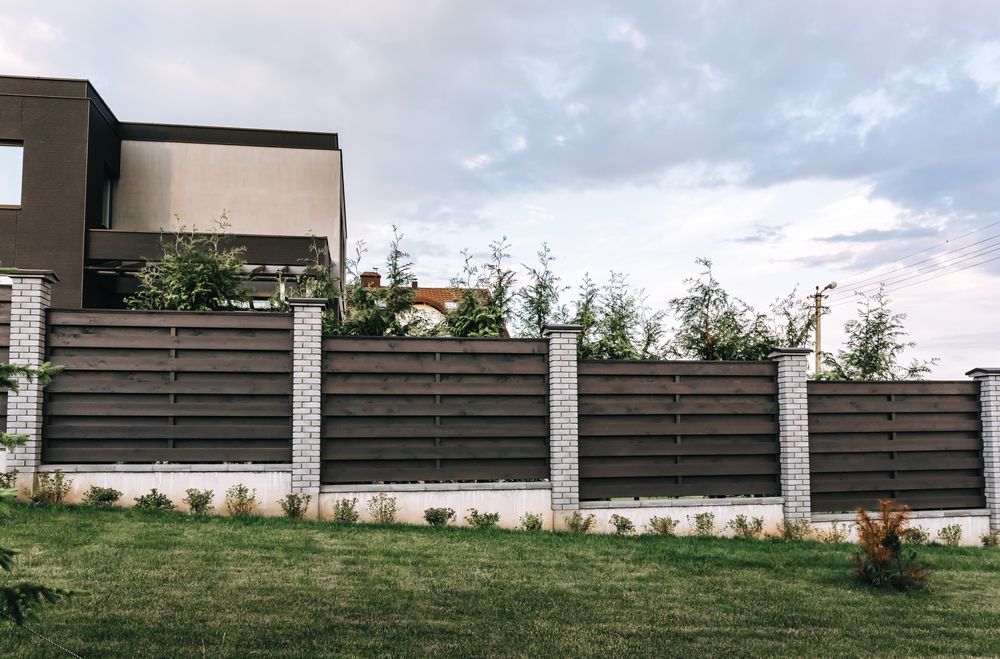 A Dark Wooden Fence With Concrete — Smiddy's Services In Erina, NSW