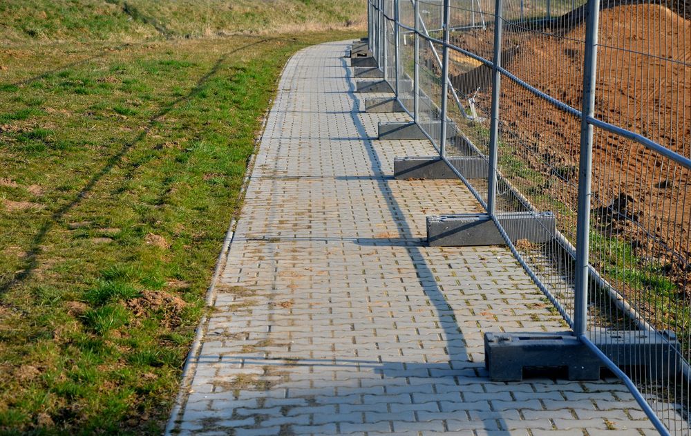 A Brick Path Beside Grass and a Temporary Metal Fence — Smiddy's Services In The Entrance, NSW