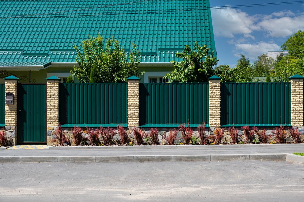 A Green Metal Fence With Brick Pillars and Matching Green Roof — Smiddy's Services In Budgewoi, NSW