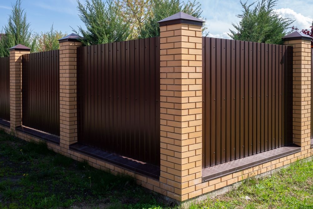 A Brown Metal Fence With Brick Pillars and a Green Lawn — Smiddy's Services In Toukley, NSW