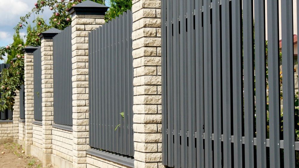 A Fence Made Of Bricks And Metal Is Surrounded By Brick Pillars — Smiddy's Services In Wyong, NSW