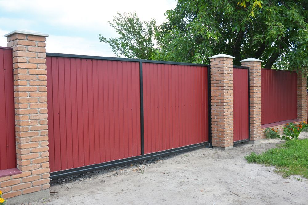 A Red Metal Gate and Fence With Brick Columns, in a Yard — Smiddy's Services In Tacoma, NSW