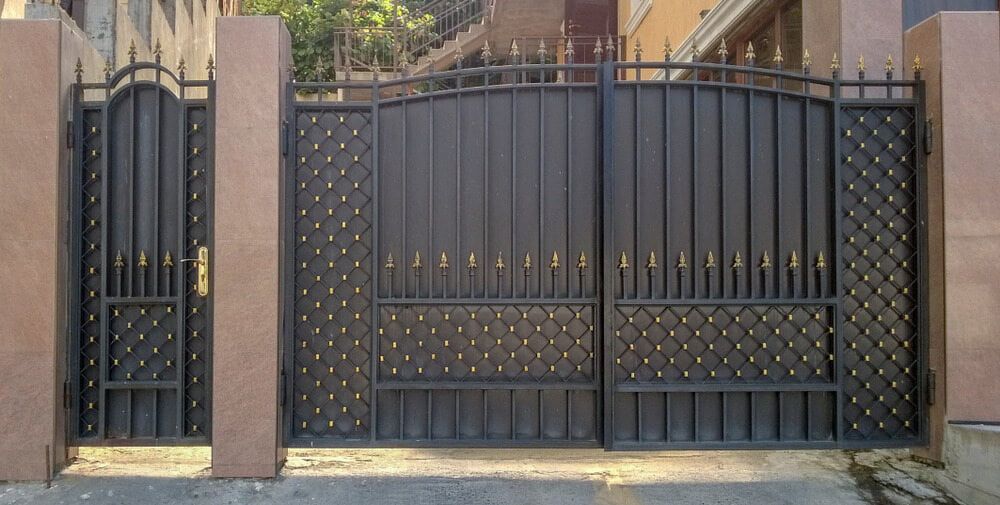 A Wrought Iron Gate Is Surrounded By Stone Pillars — Smiddy's Services In Lake Macquarie, NSW