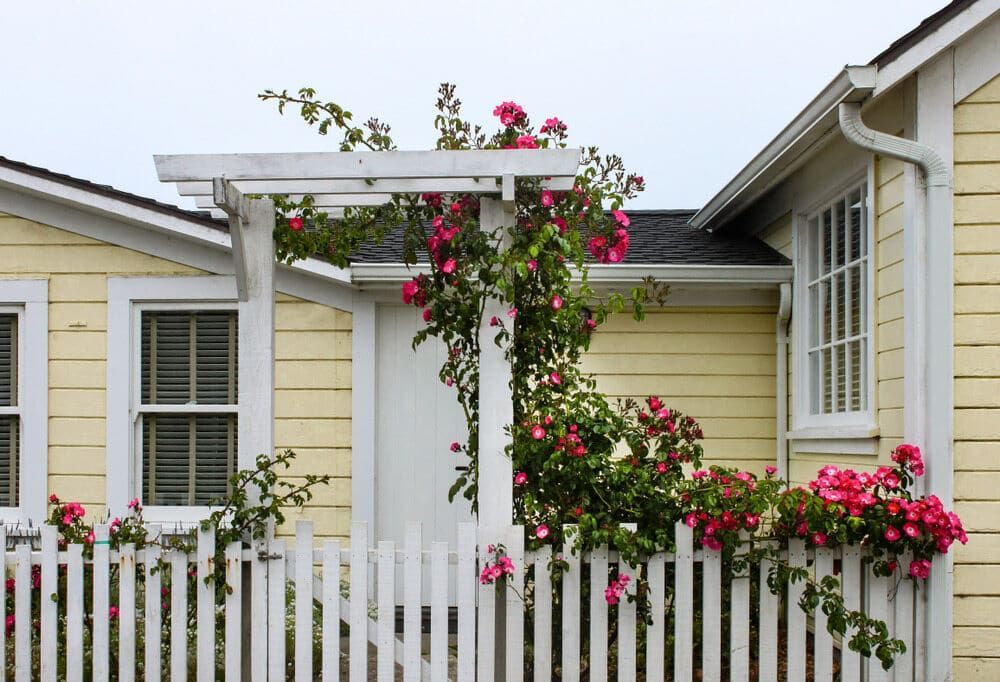A White Picket Fence Is In Front Of A Yellow House — Smiddy's Services In Wyong, NSW