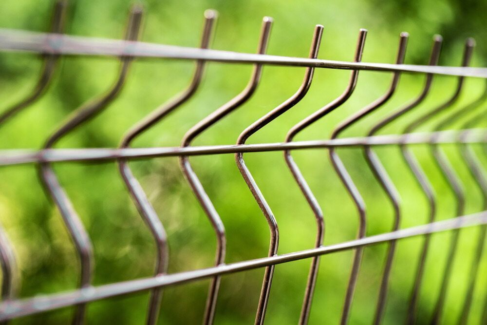 A Close Up Of A Wire Fence With A Green Background — Smiddy's Services In Wyong, NSW