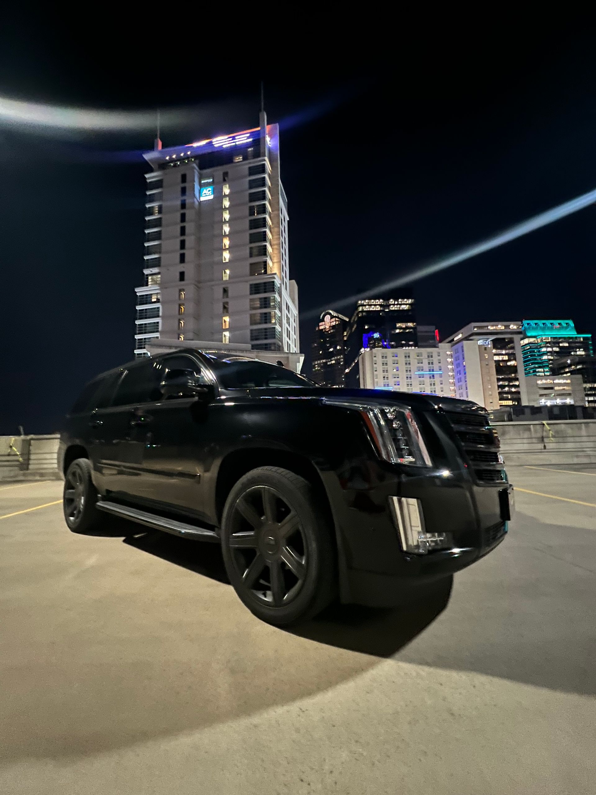A black suv is parked in a parking lot at night