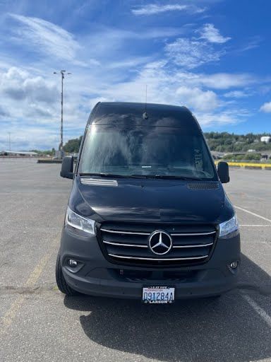 A black mercedes sprinter van is parked in a parking lot.