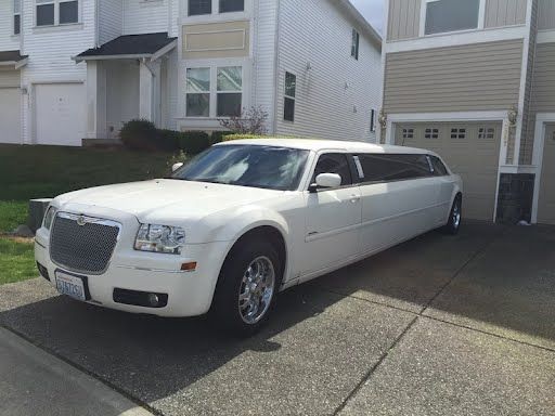 A white limousine is parked in front of a house.