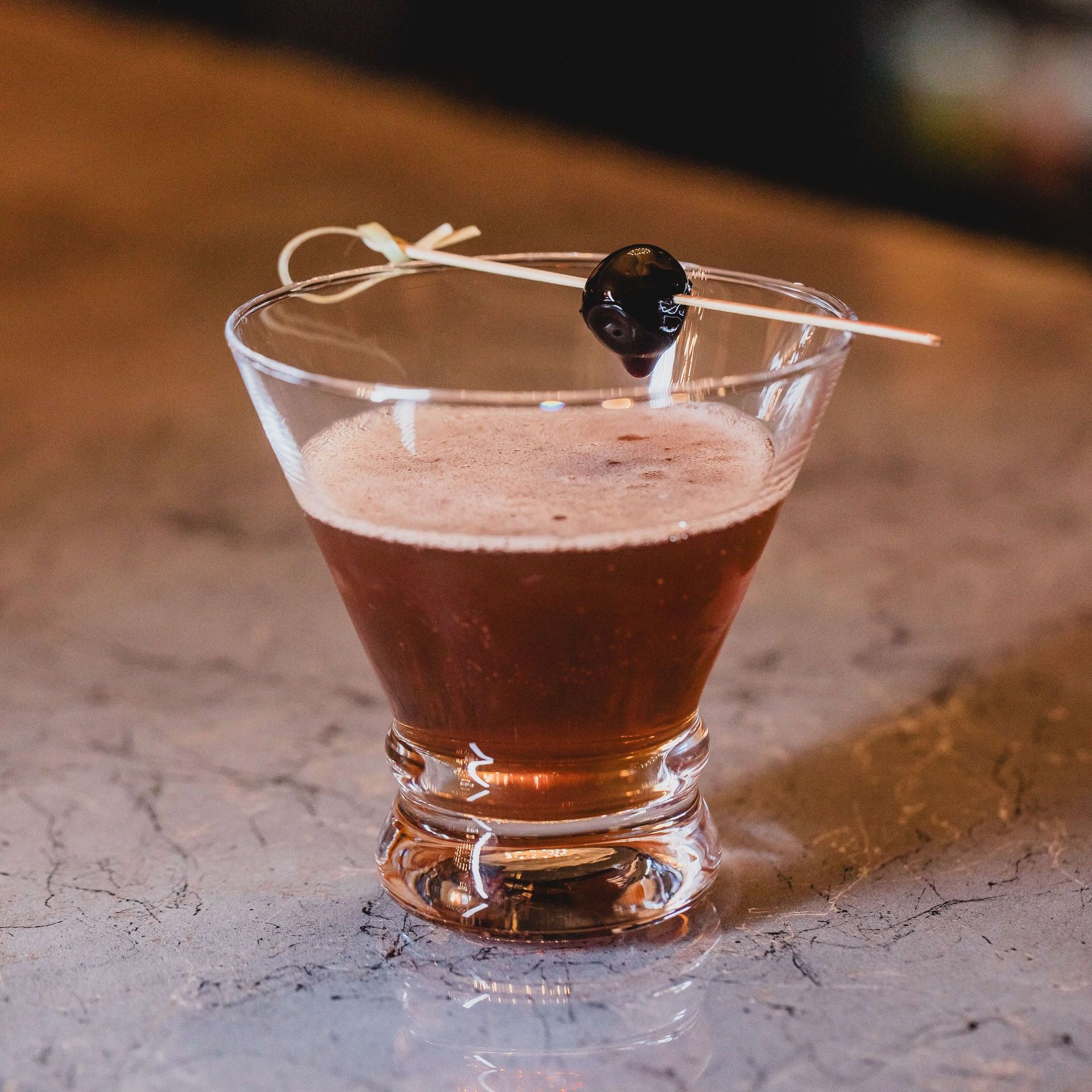 an Oldfashioned cocktail with a cherry on a toothpick in it