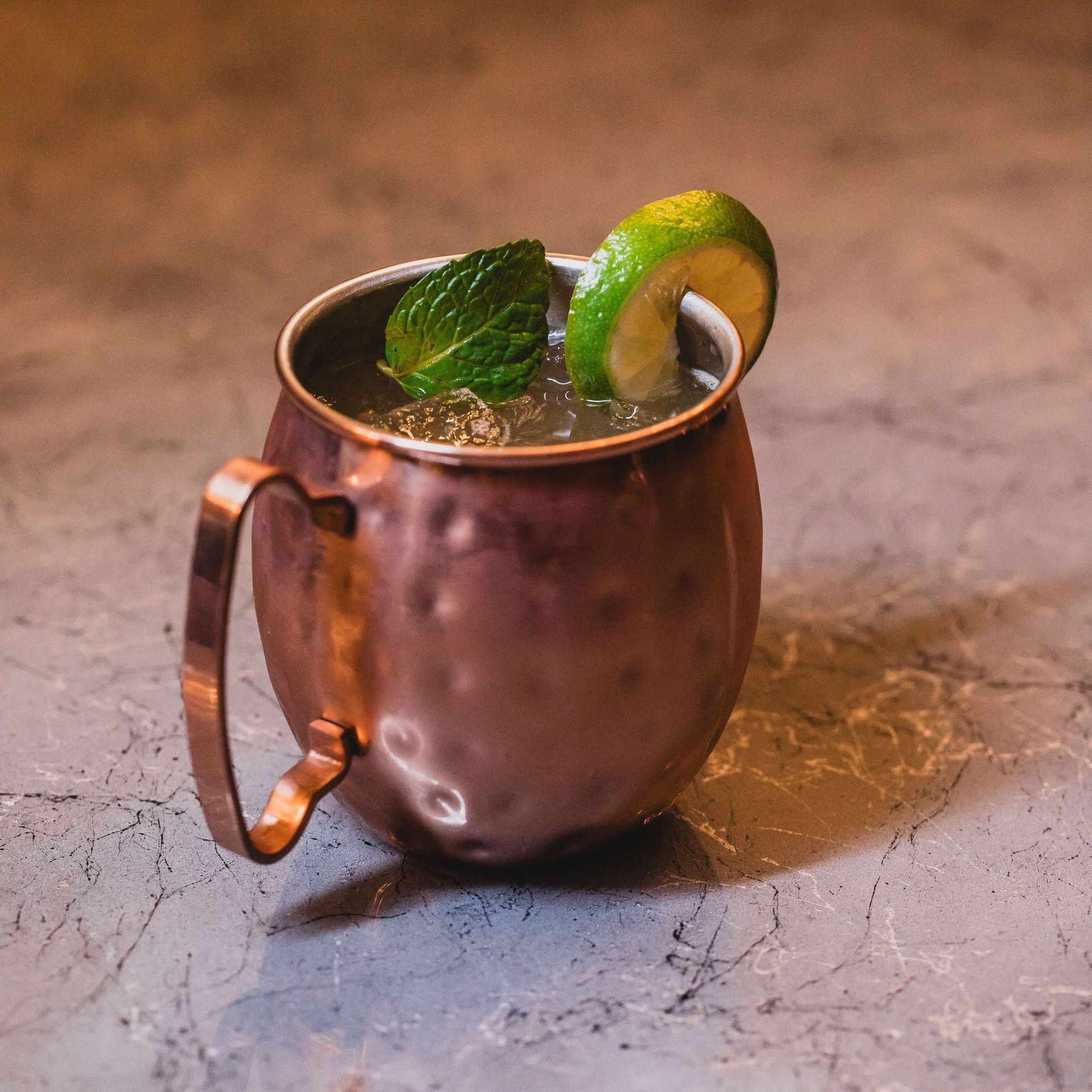 a close up of a copper mug filled with a drink on a wooden table .