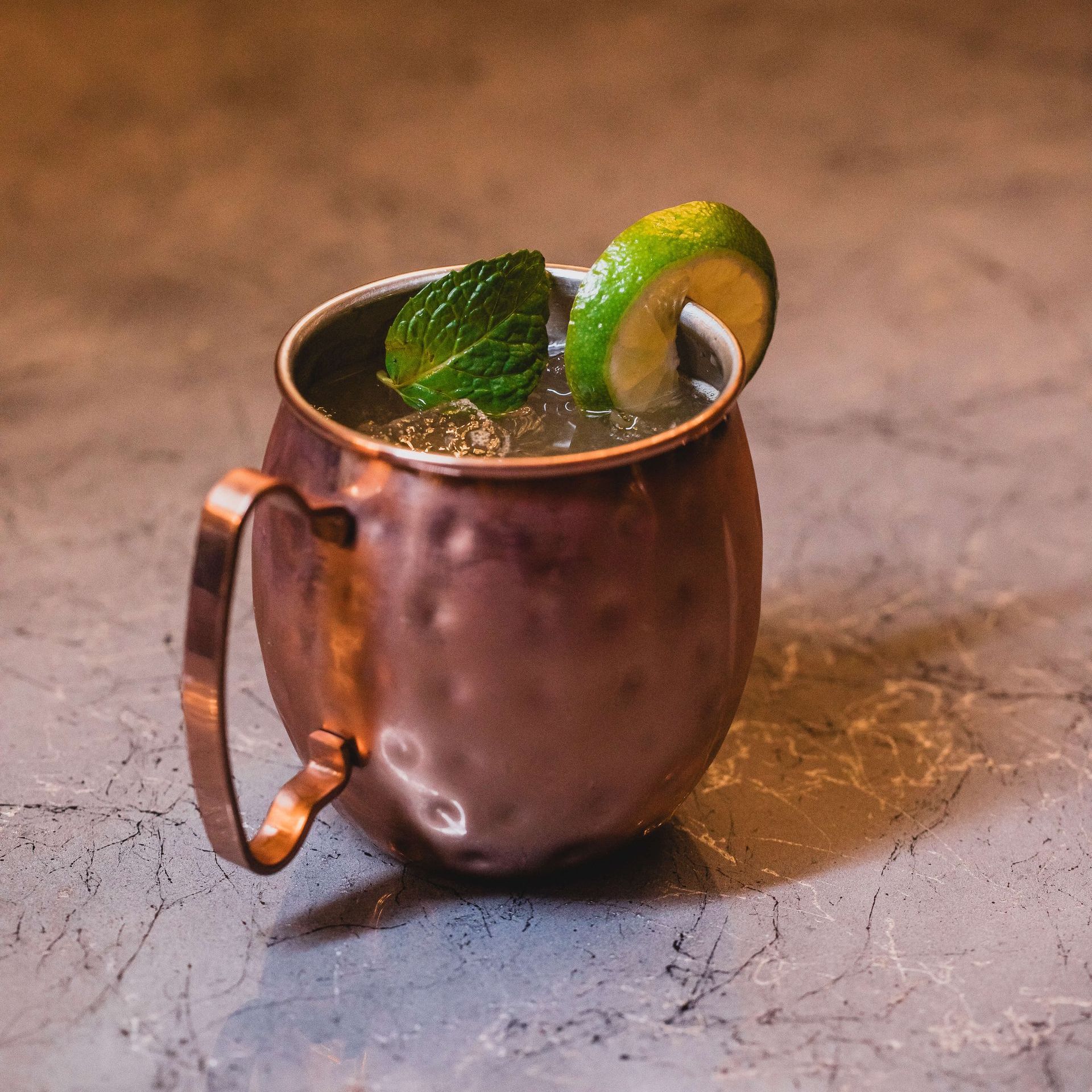 a close-up of a copper mug filled with a drink on a wooden table.