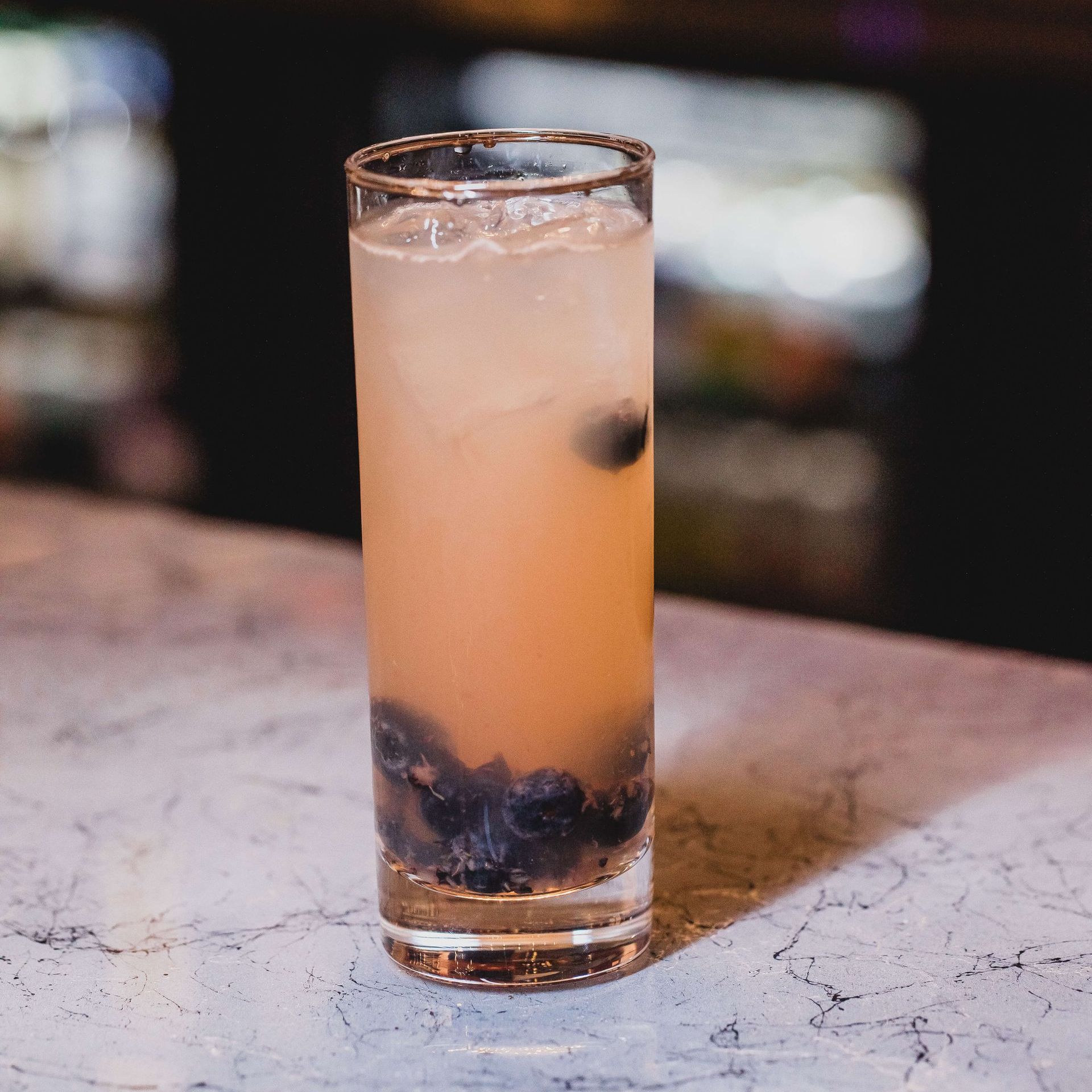 a close-up of a Melissa's Blueberry Bourbonade drink with blueberries and mint leaves