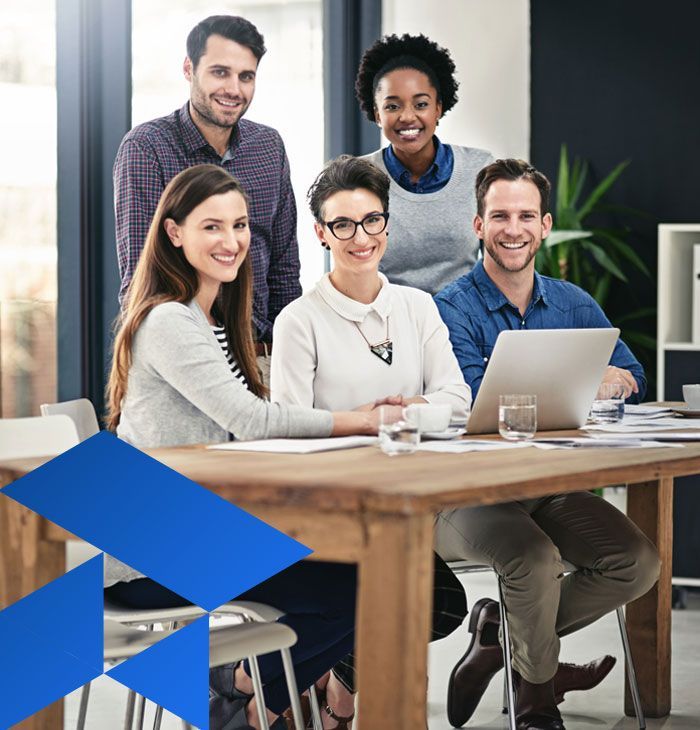 A group of people are sitting around a table with a laptop.