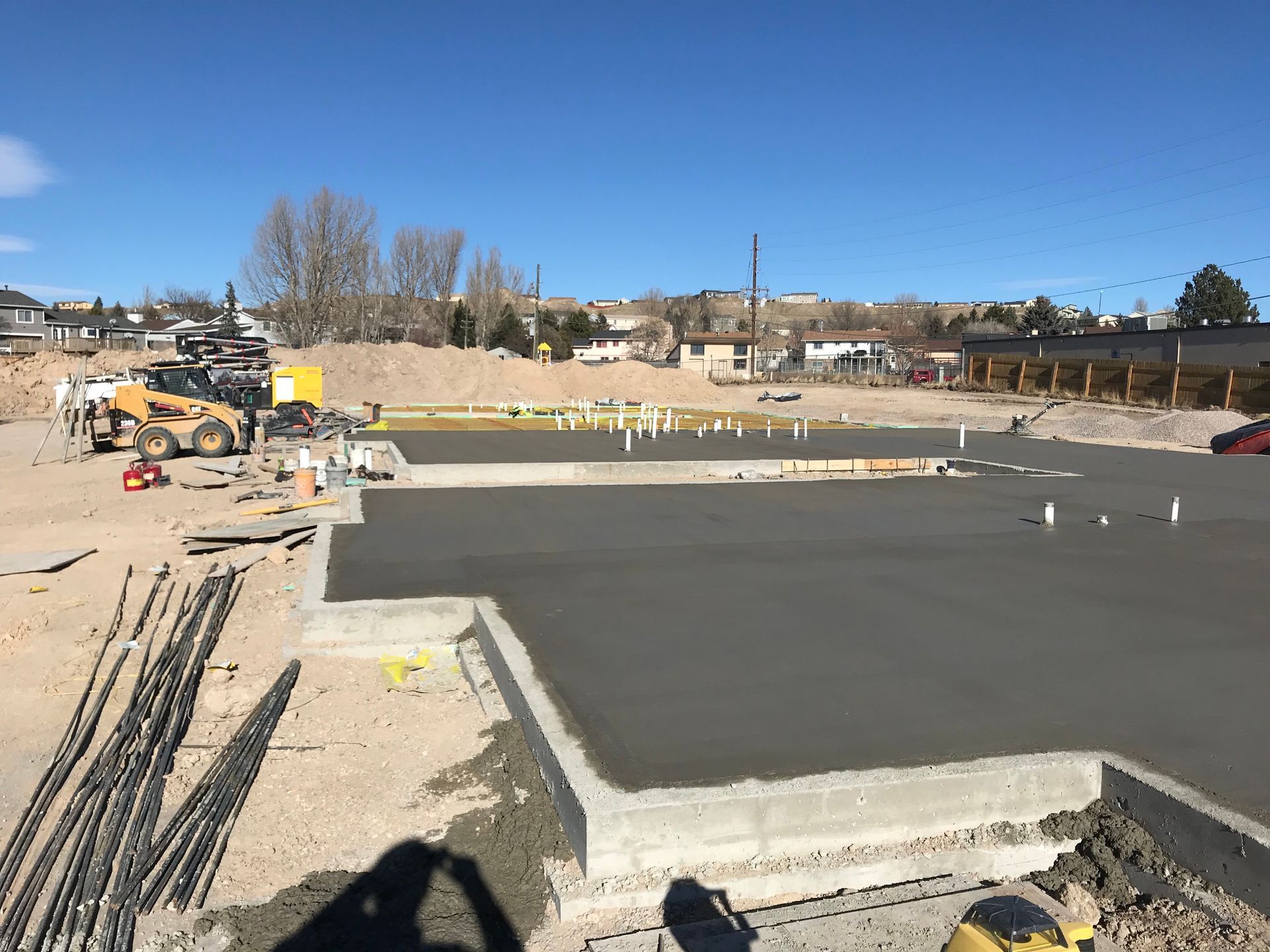 Construction crane next to a metallic, angular building under a pale blue sky.
