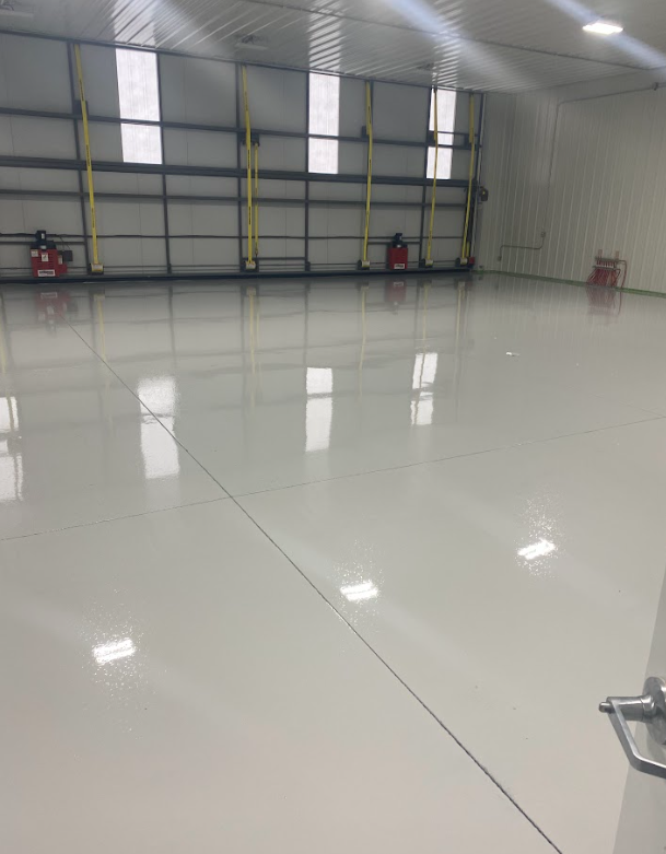 Person using a plate compactor on wet concrete, outdoor construction.