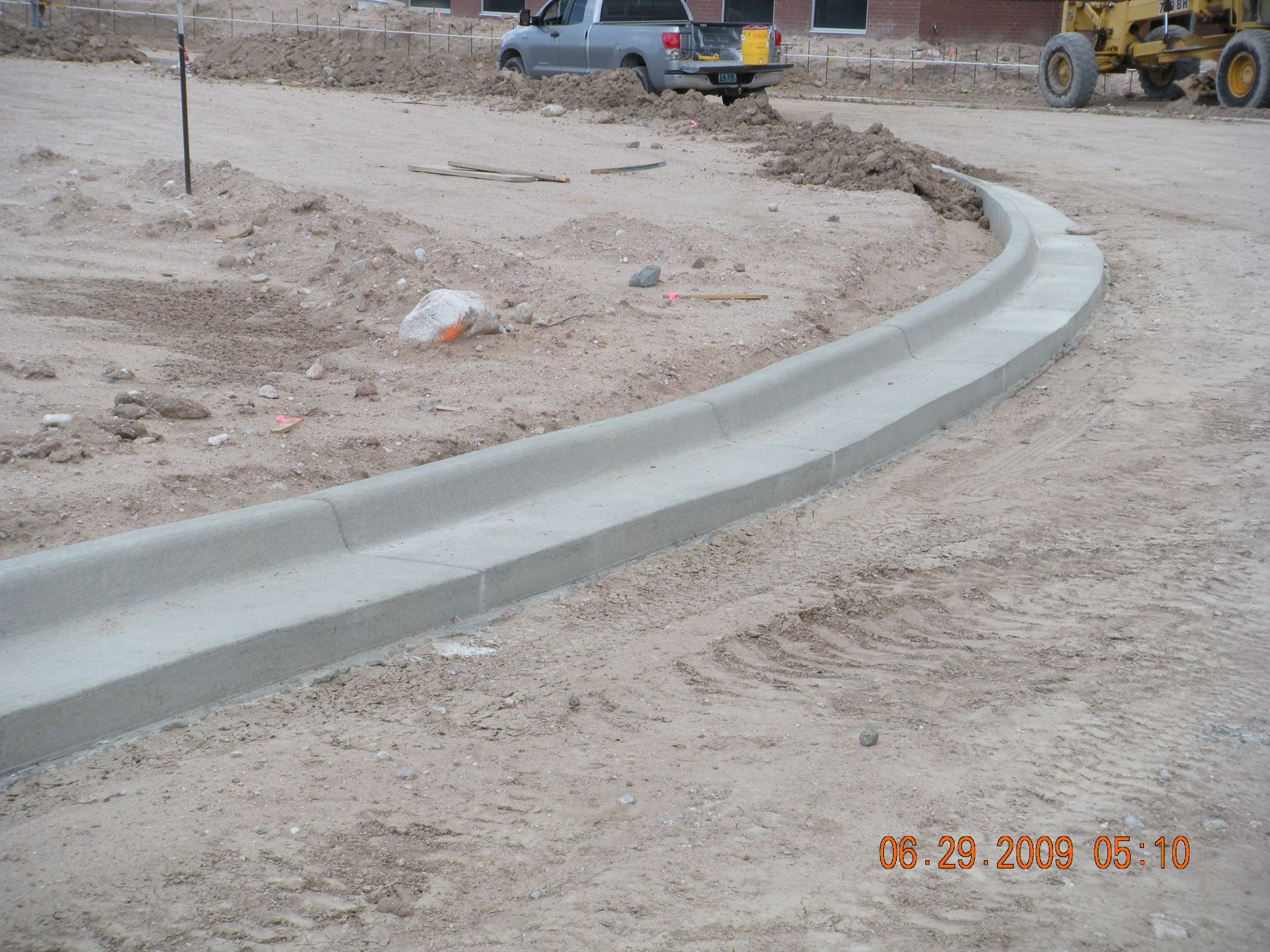 Construction site with unfinished concrete walls, stairs, and a worker laying bricks.