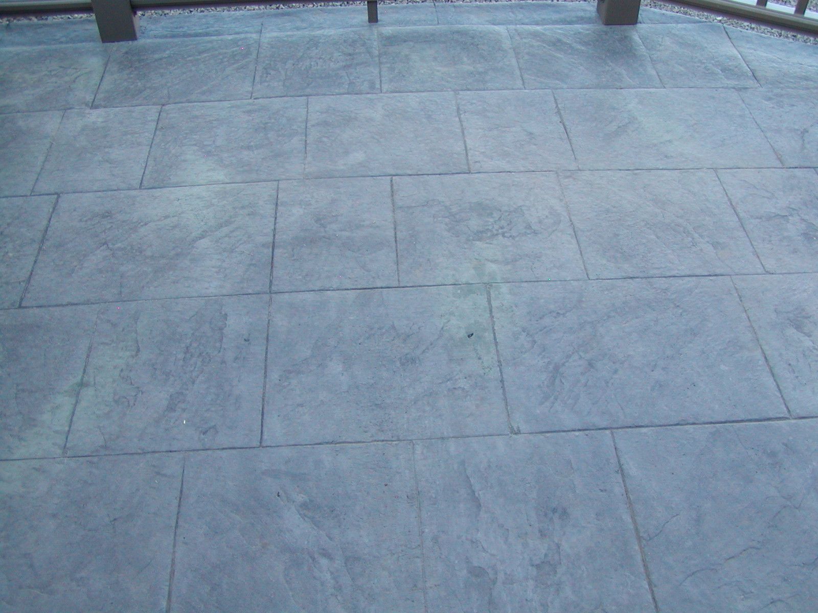 Textured gray concrete patio with rectangular tile pattern.