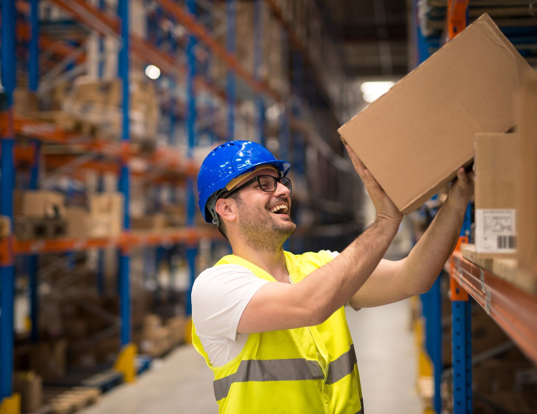 A man is lifting a box in a warehouse.