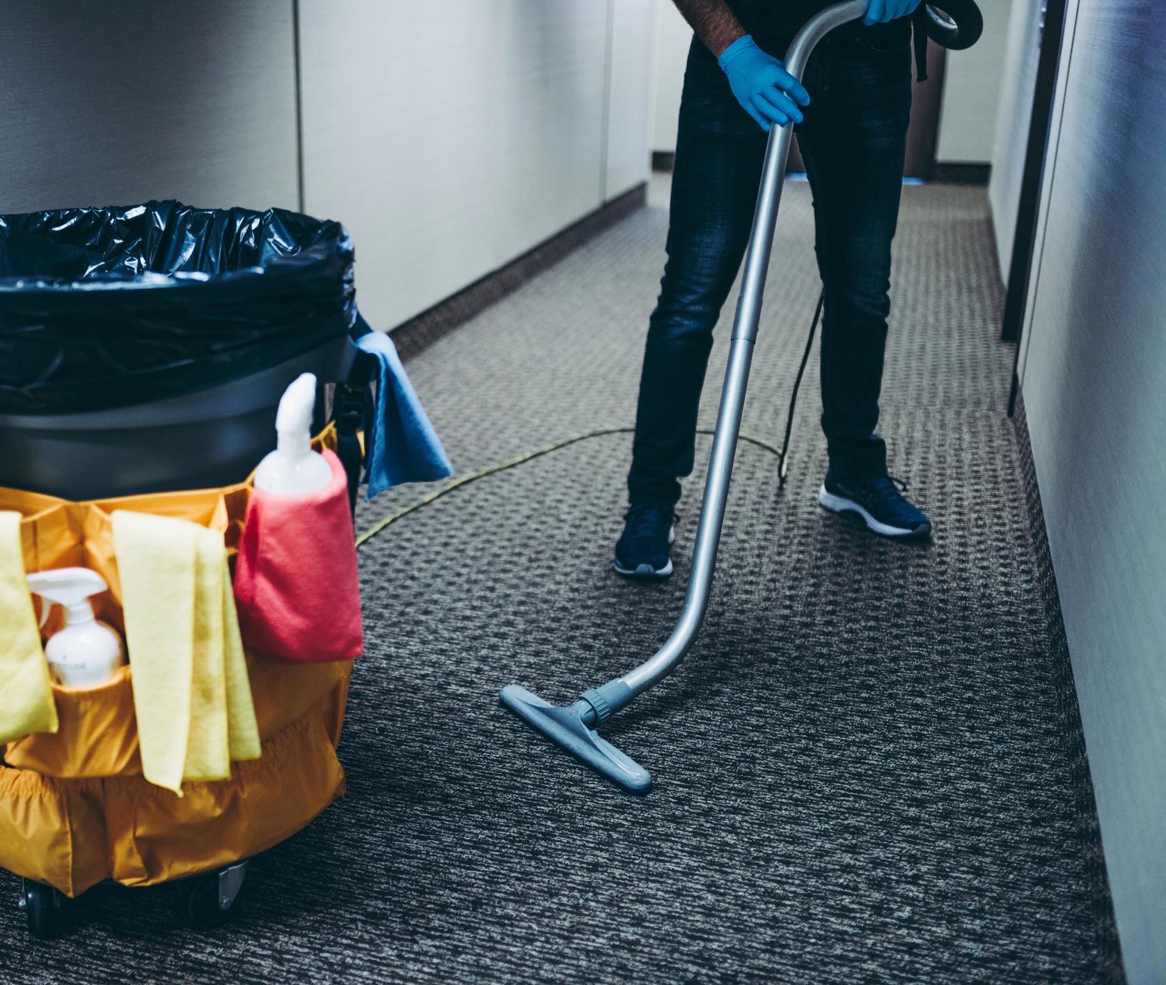 A man is using a vacuum cleaner to clean a hallway.