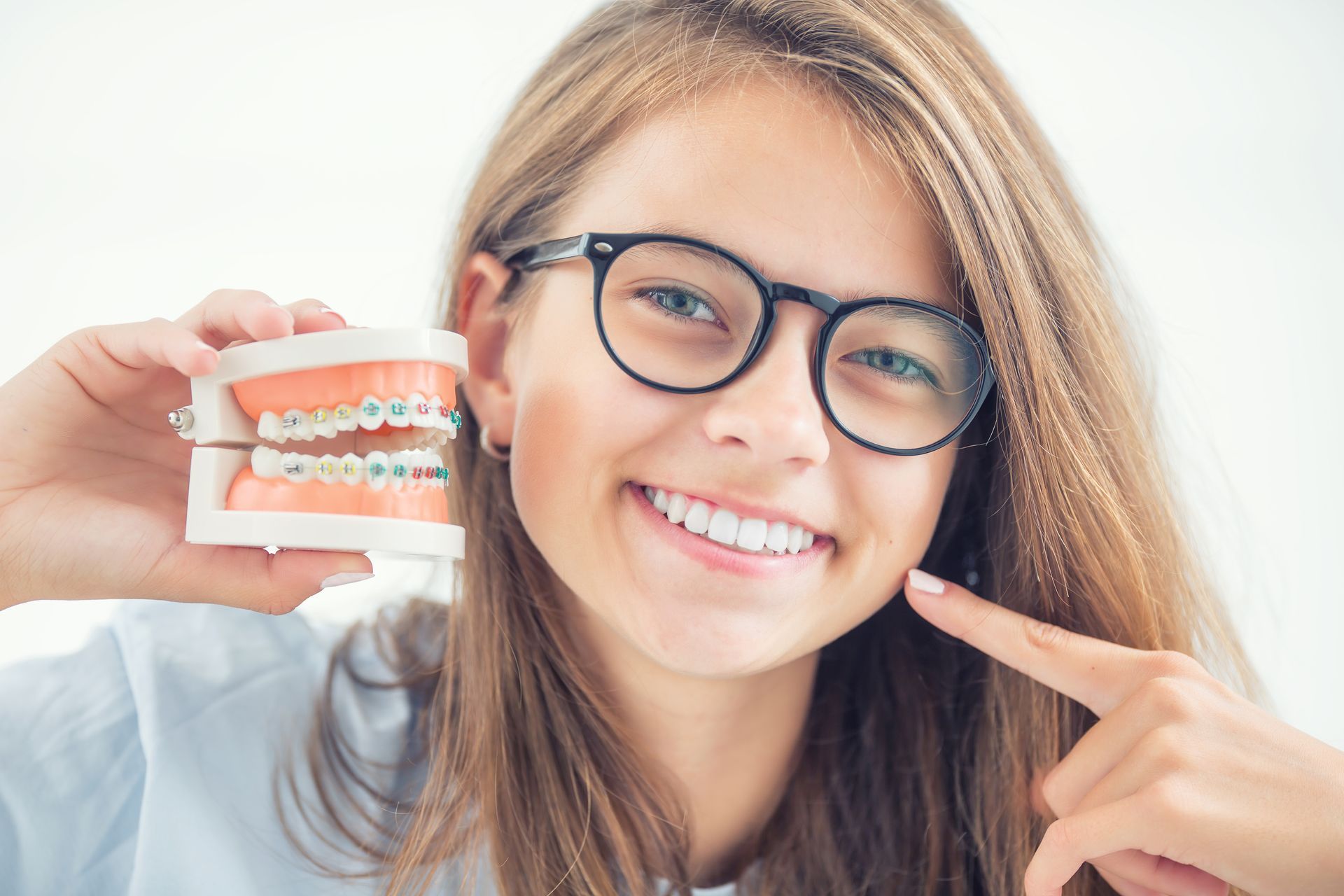 Model of a dental braces in the hand of a young girl with aligned teeth after the process of using a dental brace.