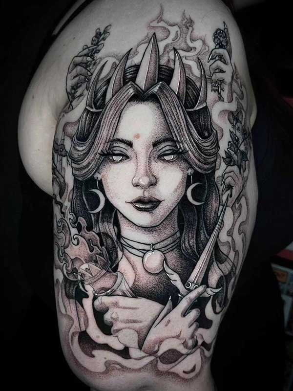 A black and white tattoo of a woman with horns and a crown on her head.