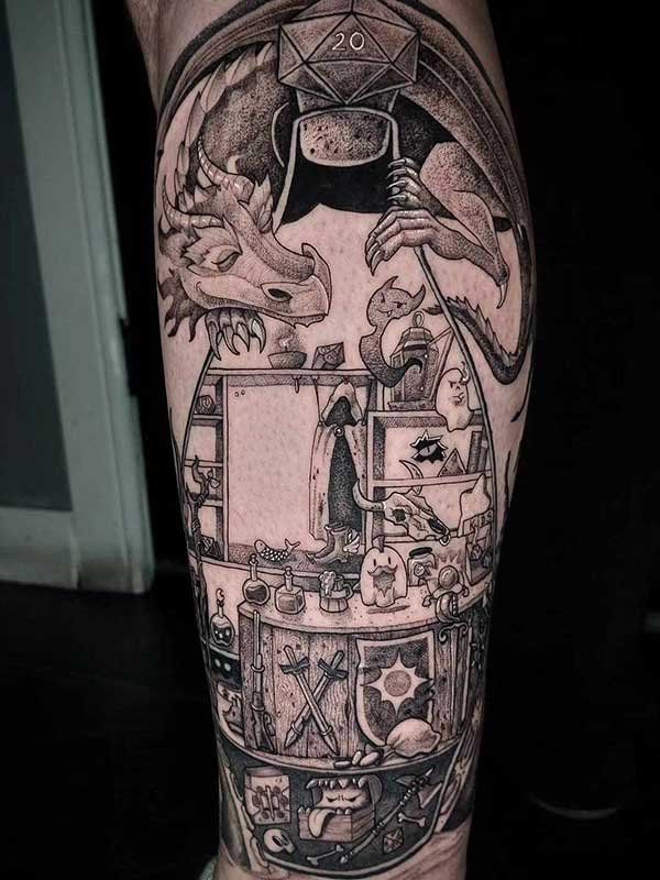 A black and white tattoo of a dragon holding a d20 on a person 's leg.