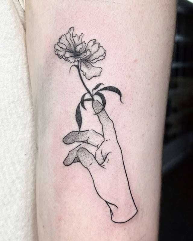A tattoo of a hand holding a flower on a person 's arm.