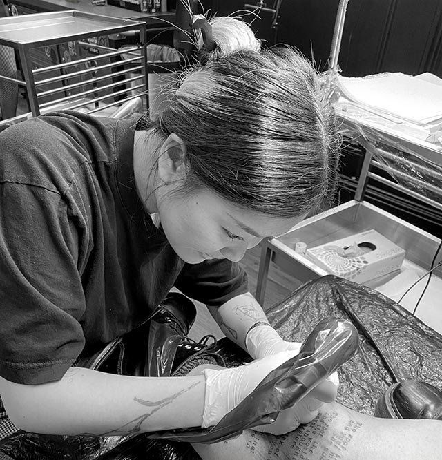 A woman is working on a pair of shoes in a black and white photo