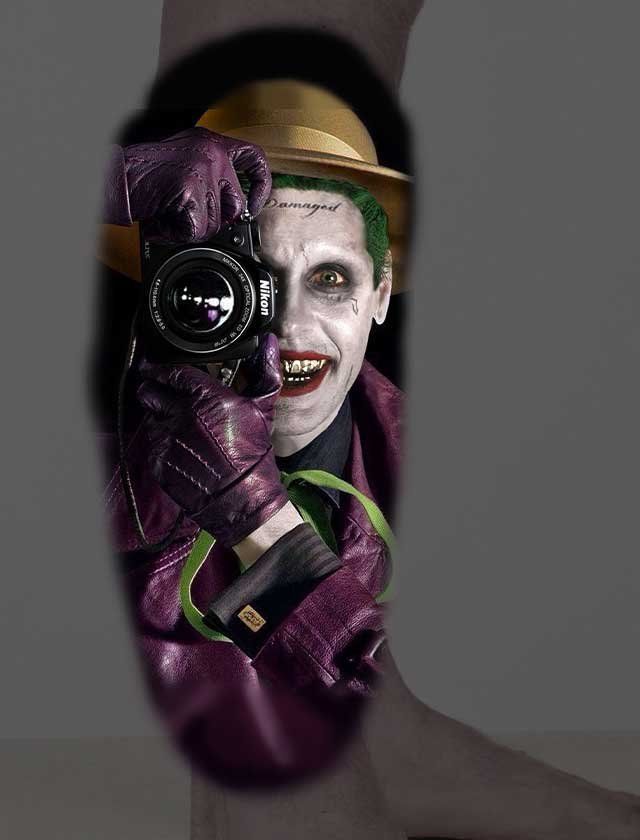 A tattoo of the joker taking a picture with a camera.