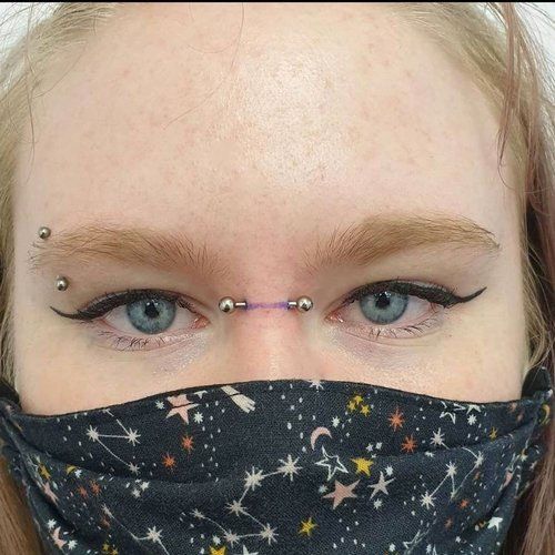 A close up of a woman 's face with a mask and piercings.