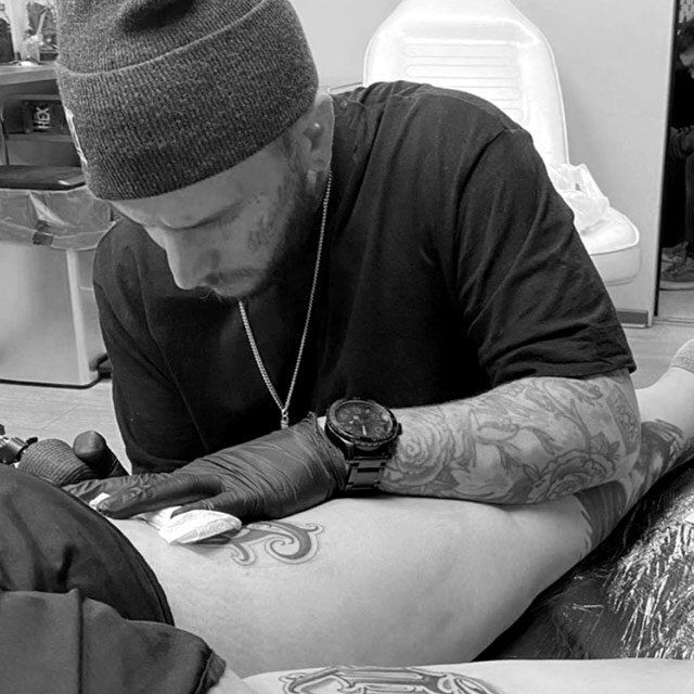 A man is getting a tattoo on a person 's leg.