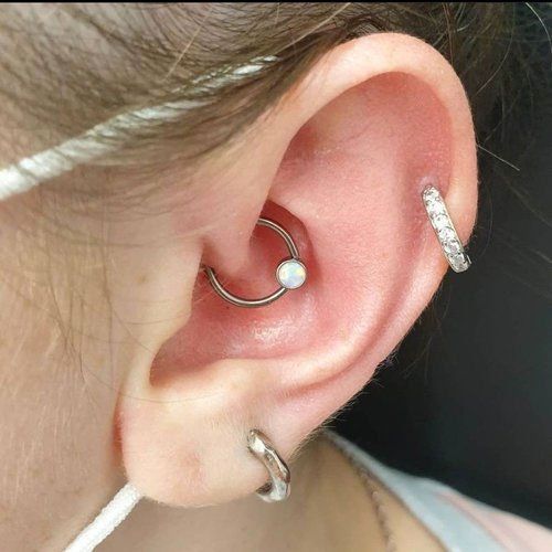 A close up of a woman 's ear with multiple piercings.