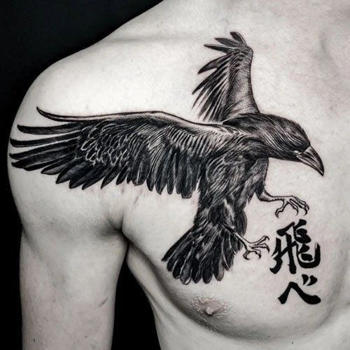 A man has a black and white tattoo of a crow on his chest.