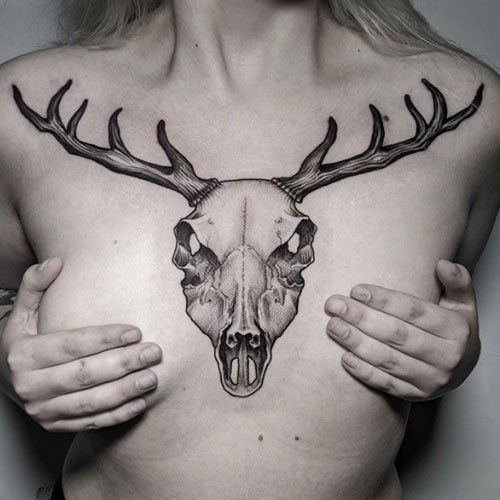 A woman has a tattoo of a deer skull on her chest.