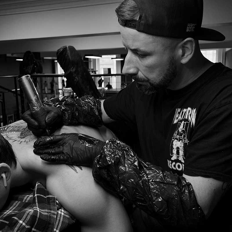 A man is getting a tattoo on another man 's back