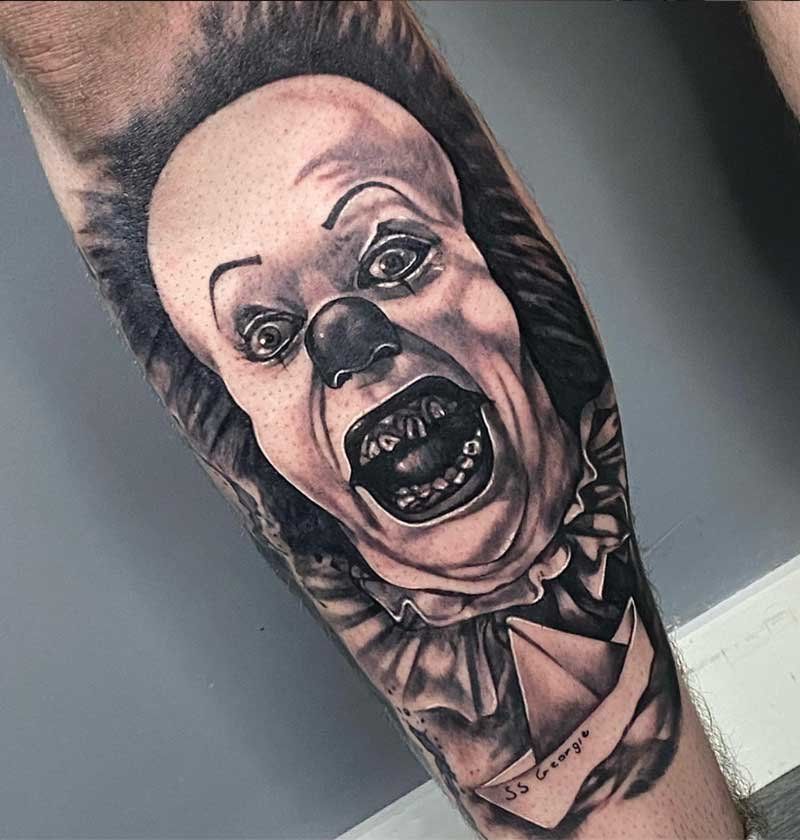 A black and white tattoo of a clown on a leg.