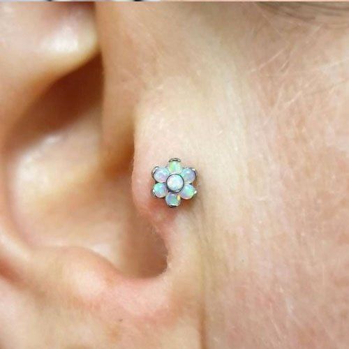 A close up of a person 's ear with a flower shaped earring.